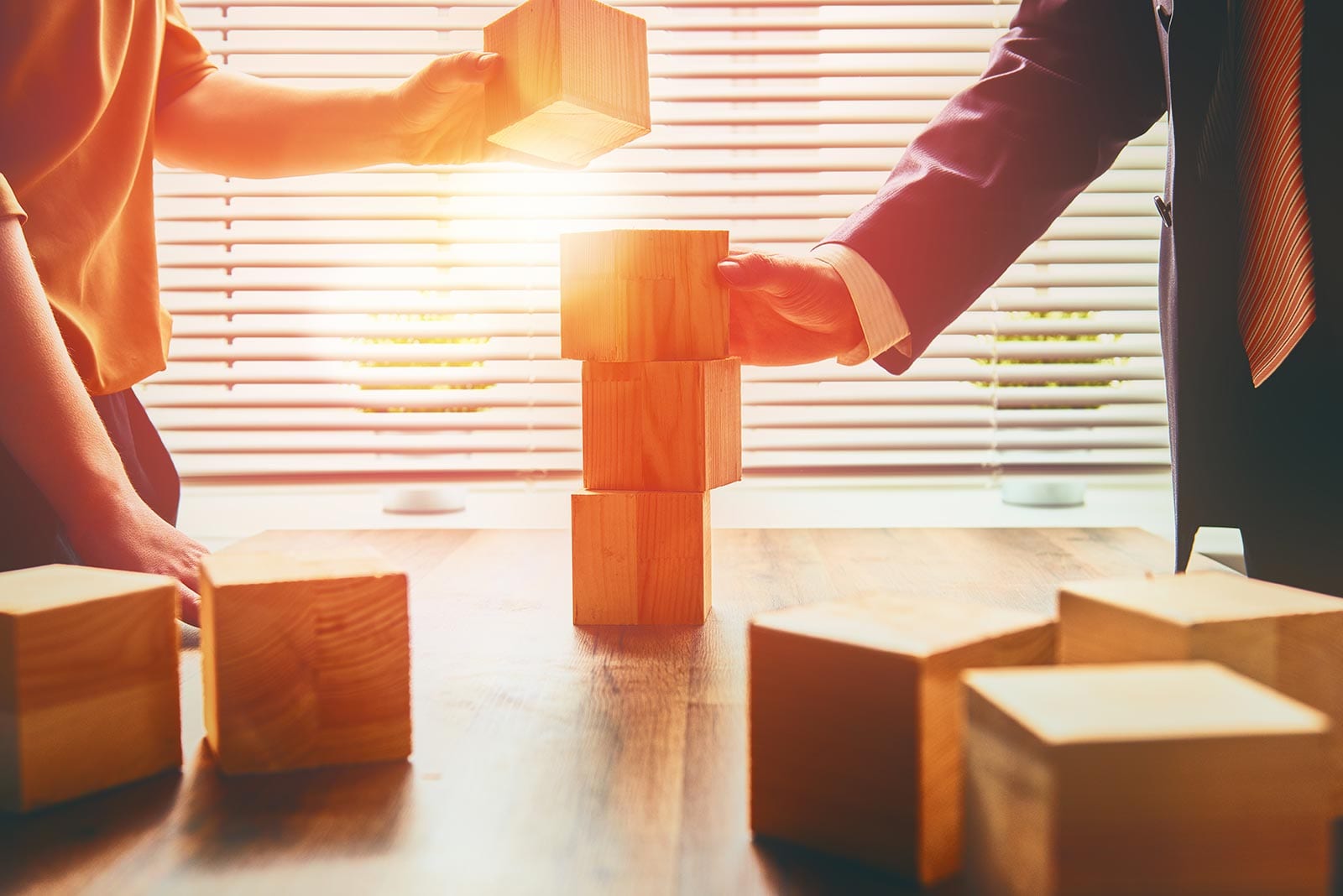 Two business professionals stacking wooden blocks to symbolize building the right DDI and DNS solution strategy