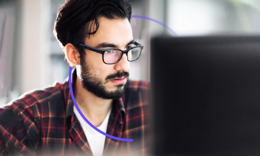 A man with glasses looks at a screen