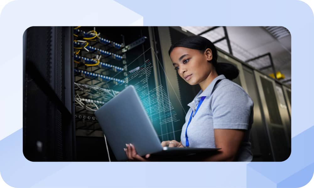 Network engineer reviews DDI observability data on laptop in server room, with code overlay on racks